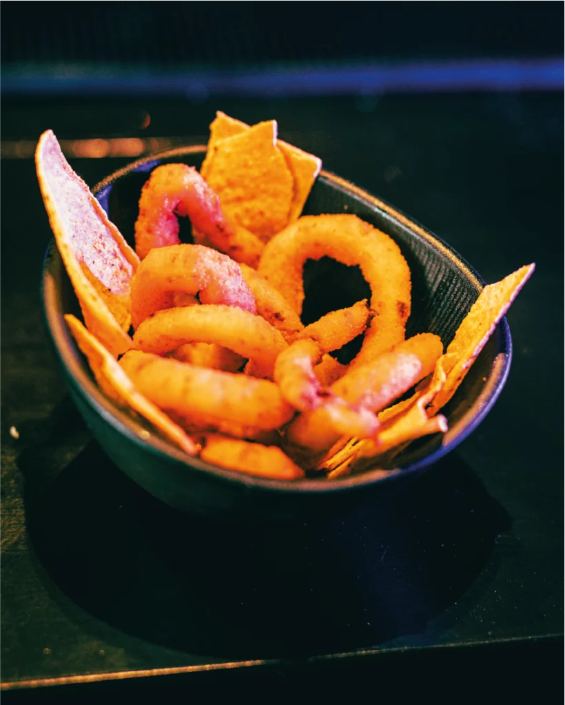 Ciotola nera con anelli di cipolla fritti e nachos al La Diosa.