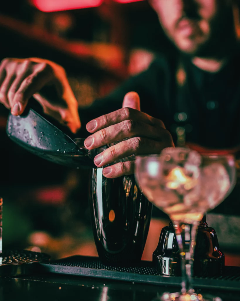 Bartender che prepara un cocktail con bicchiere e shaker sul bancone al La Diosa.